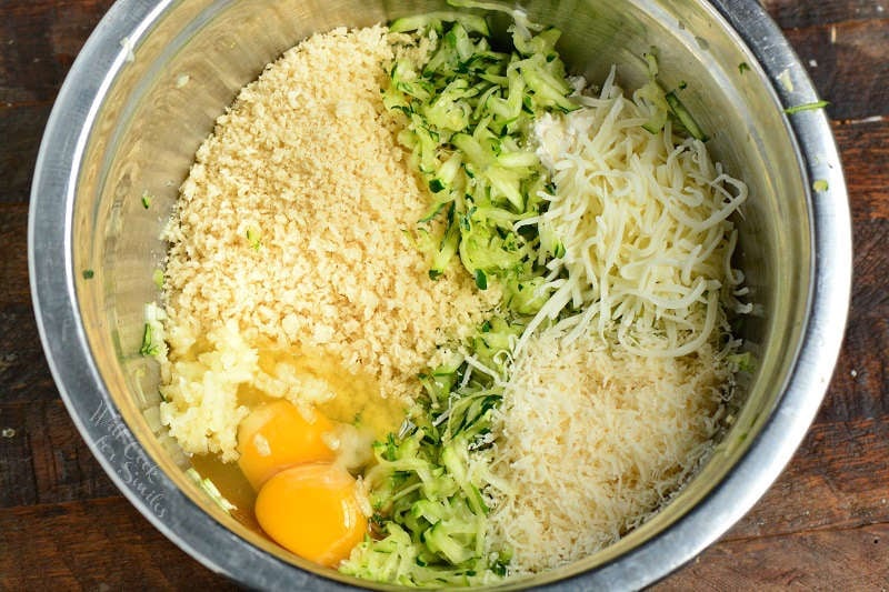 egg, zucchini, bread crumbs, and cheese in a metal bowl 