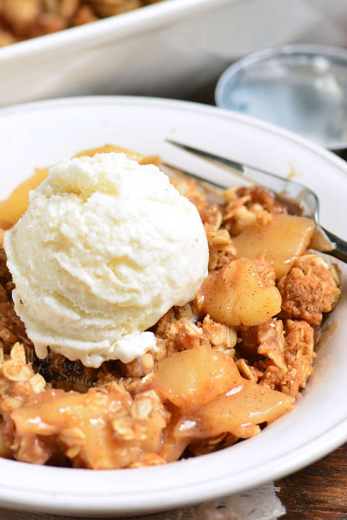 apple crisp in a bowl topped with ice cream in a bowl with a fork 