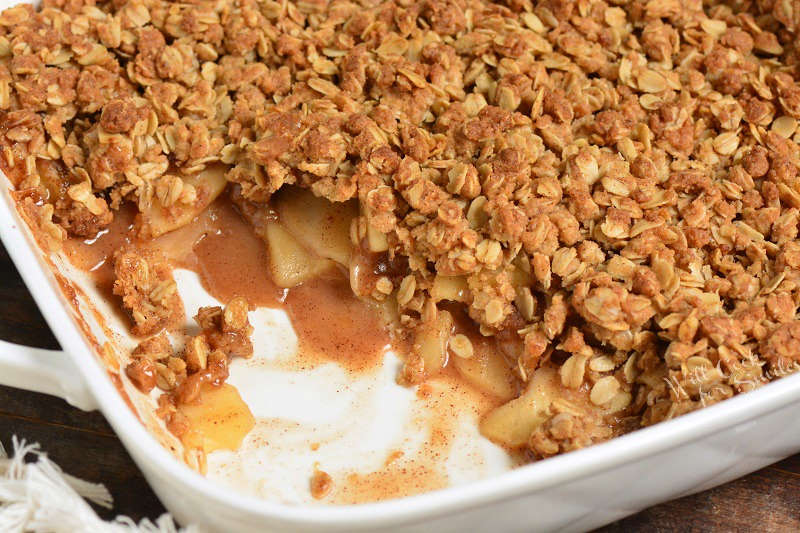 baked apple crisp with a piece taken out in a baking dish 