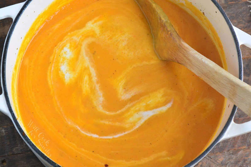 creamy butternut squash soup in a pot with a wooden spoon