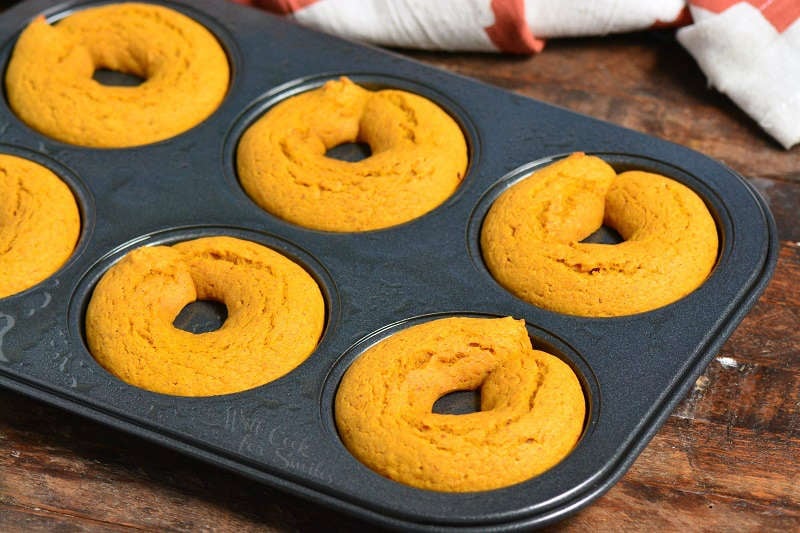 baked pumpkin donuts in a donut pan on a wood table 