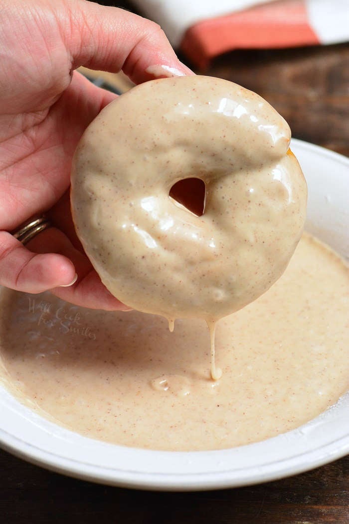 dipping pumpkin donuts in glaze that is in a bowl 