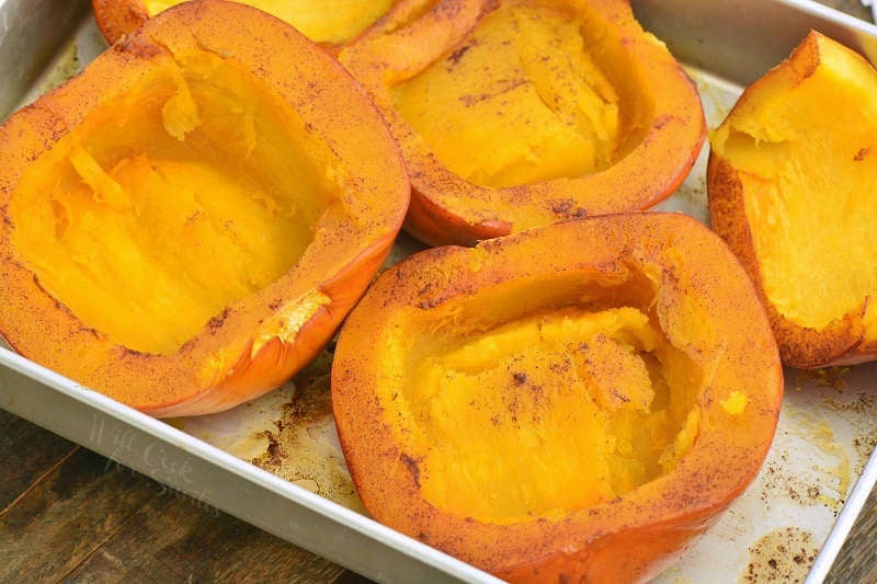 inside of baked sugar pumpkin halves in a baking pan.