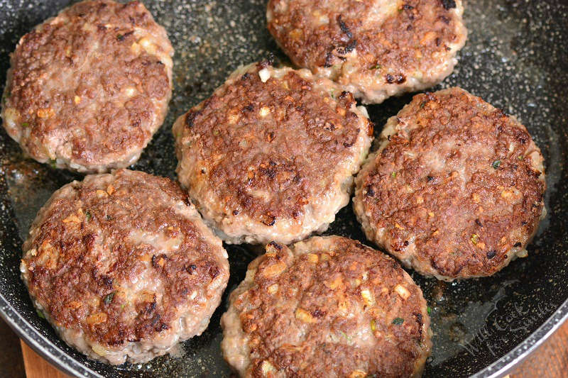 searing salisbury steaks cooking in a pan 