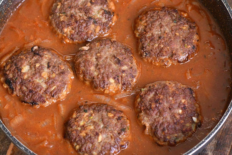 adding partially cooked Salisbury steaks into the pan with French onion sauce.