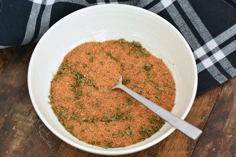 pork seasoning in a bowl on a wood table with a blue and white table cloth 