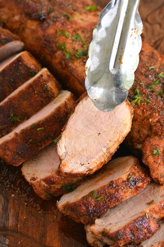 pork tenderloin slice being picked up by tongs 