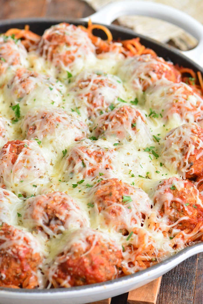 spaghetti and meatballs casserole in a pan on a wood cutting board 