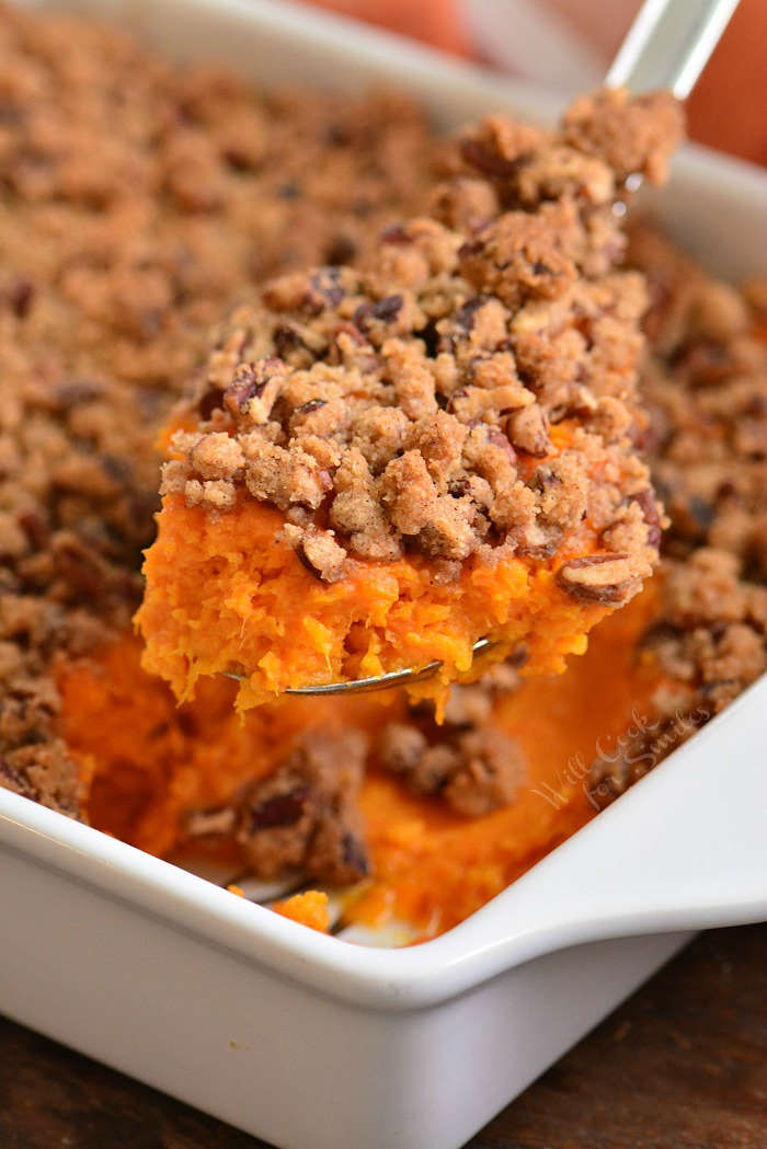 scooping out some sweet potato casserole from a pan.