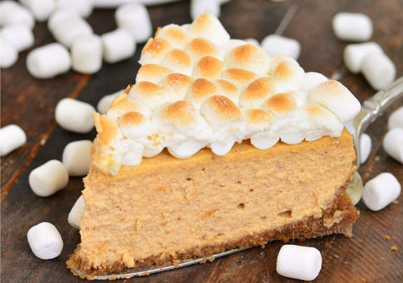 sweet potato cheesecake slice on a wood cutting board surrounded by mini marshmallows 