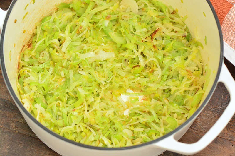 sauteed leeks in a pot on a wood table 