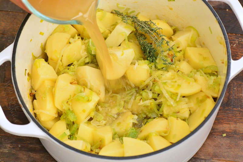 adding broth to the soup that is in a pot 
