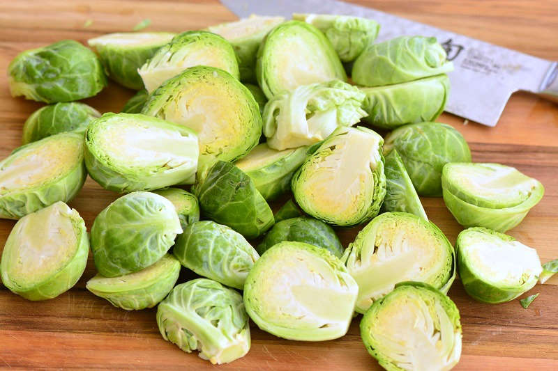 sliced brussels sprouts on a wood cutting board with a knife 