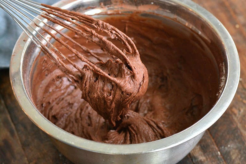 brownie batter in a metal bowl with a metal whisk 