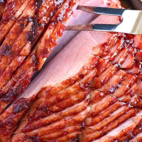 spiral cut ham with a big fork pushing into a piece 