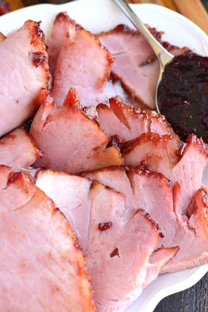 sliced baked ham with cheery glaze on platter.