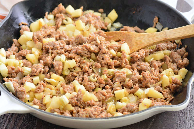 sausage and apples sautéed in a skillet.