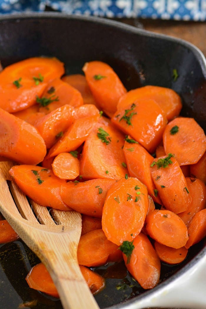 easy glazed carrots in the pan with a wooden spoon 