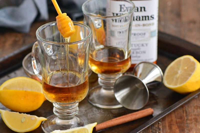 adding honey to the glass mug with bourbon.