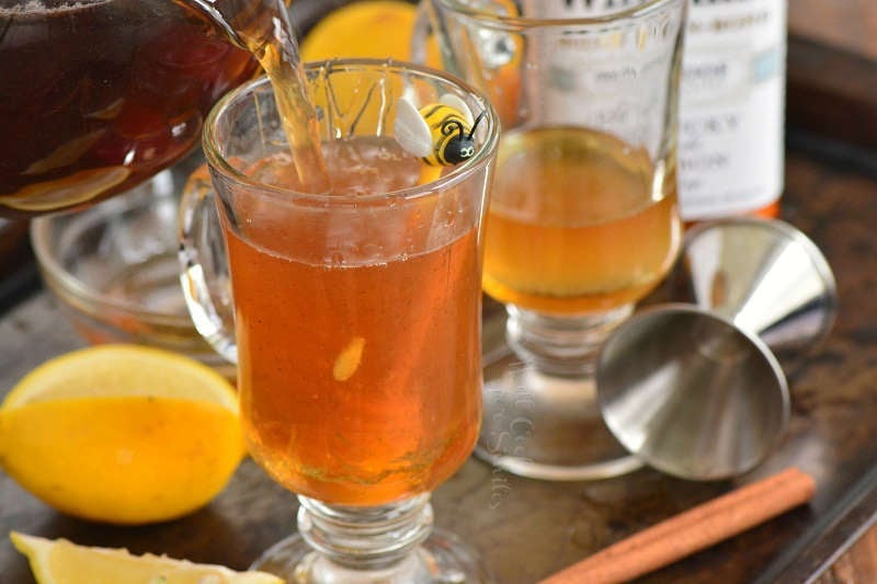 pouring in tea into the glass mug with whiskey.