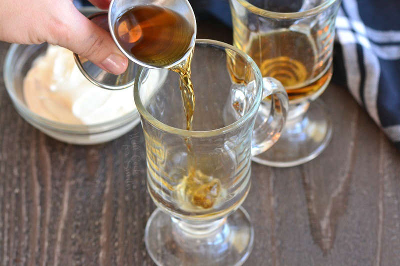 adding Irish whiskey to the glass mug.