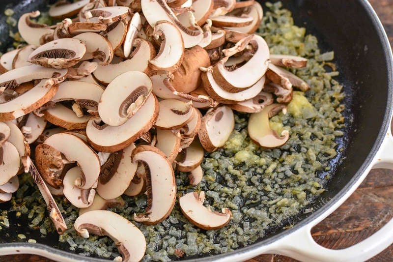 adding mushrooms to the onions and garlic in a cast iron skillet 