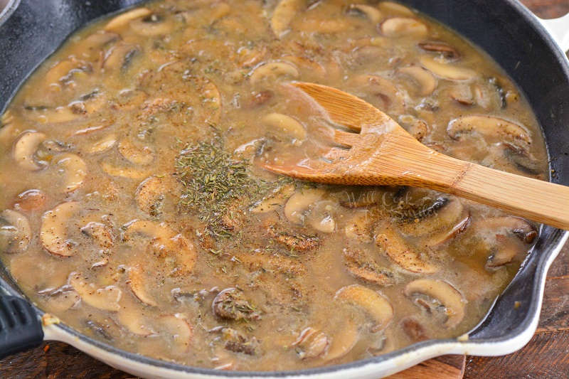 mushroom gravy in a cast iron skillet with a wooden spoon 