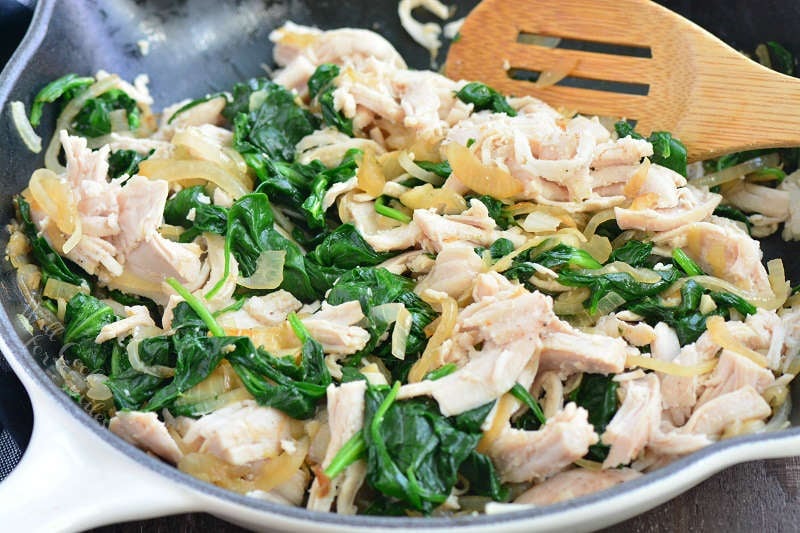 enchilada filling in a cast iron pan with a wooden spatula 