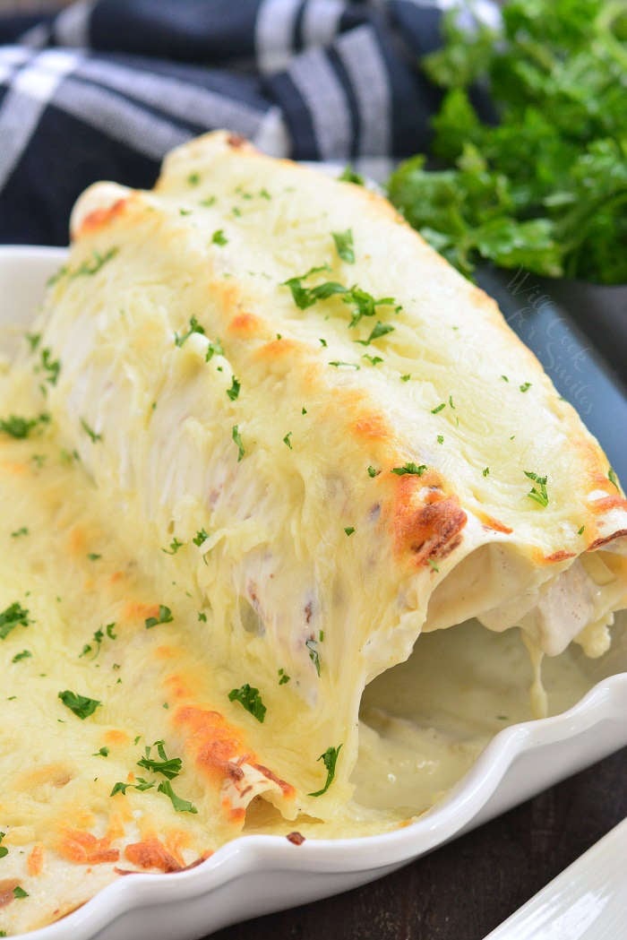 pulling out turkey enchiladas with a spatula in a casserole dish 