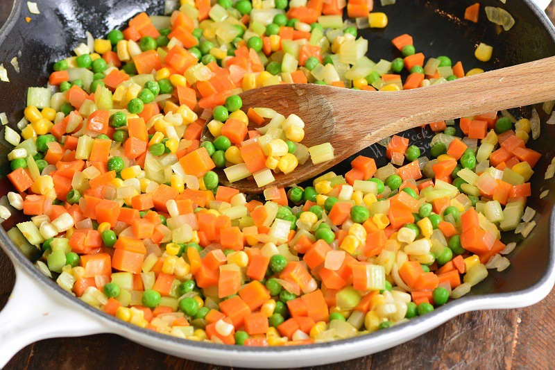 vegetables for turkey pot pie in a cast iron skillet with a wood spatula 