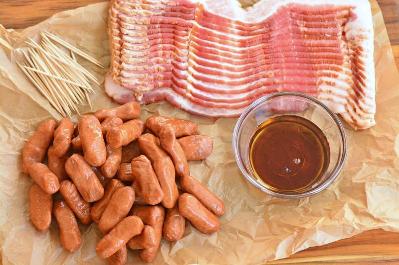 ingredients for bacon wrapped little smokies on parchment paper on a wood cutting board 