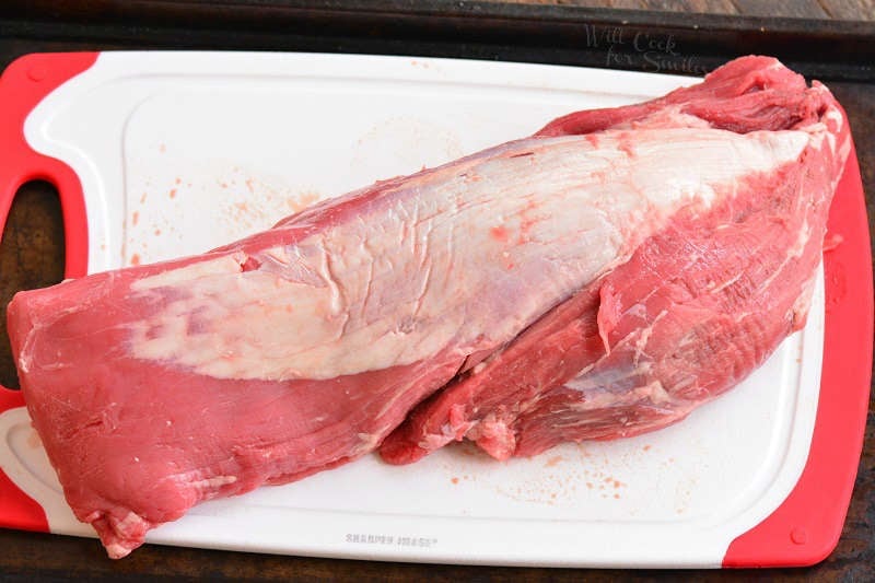 untrimmed beef tenderloin on a plastic cutting board 