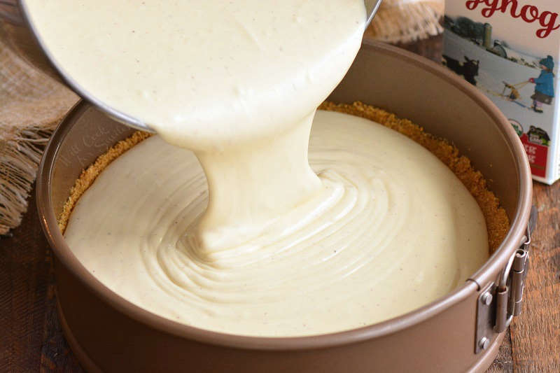 pouring cheesecake filling into the pan
