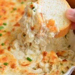scooping out some cheesy crab dip with a bread slice.