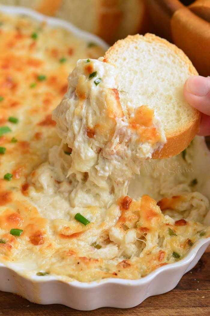 dipping crab dip out with a slice of bread