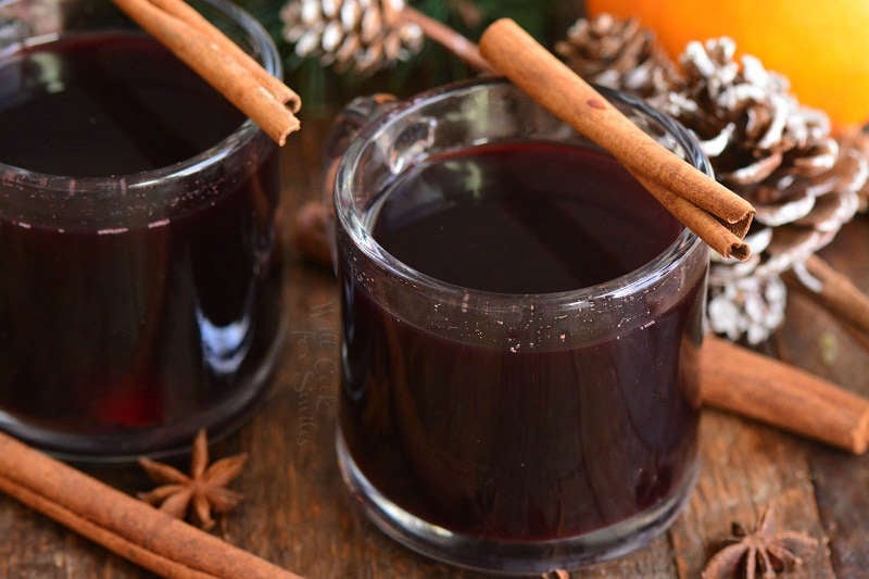 mulled wine in mugs, horizontal with cinnamon sticks over cups 