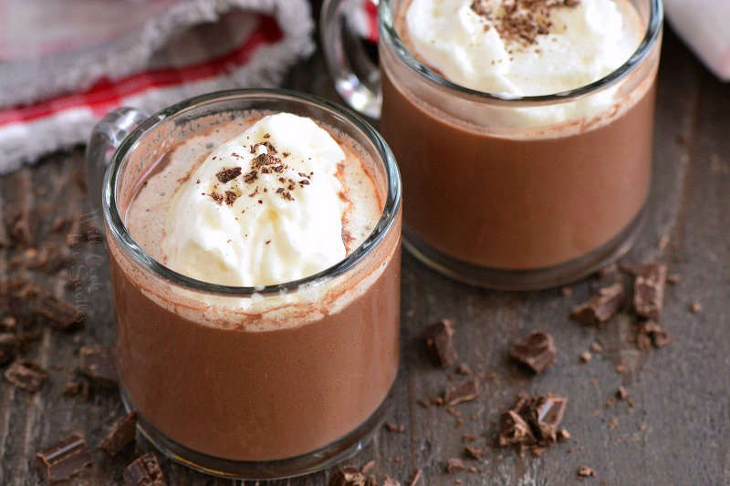 hot chocolate horizontal in glass mugs on a wood cutting board 