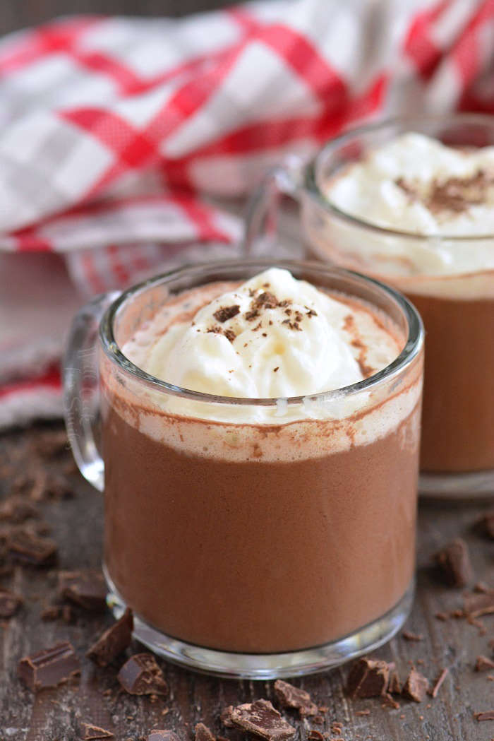 hot chocolate vertical close-up in a glass mug on a wood cutting board with chocolate shavings 