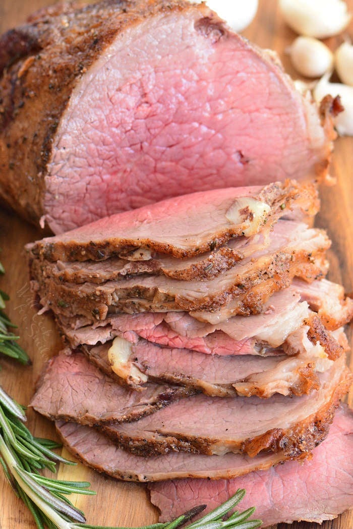 sliced roast beef vertical on a wood cutting board 