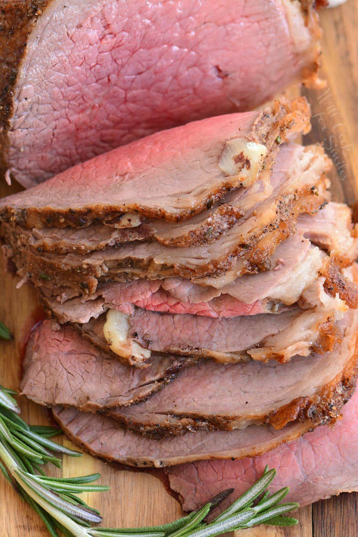 medium rare roast beef sliced on a wood cutting board 