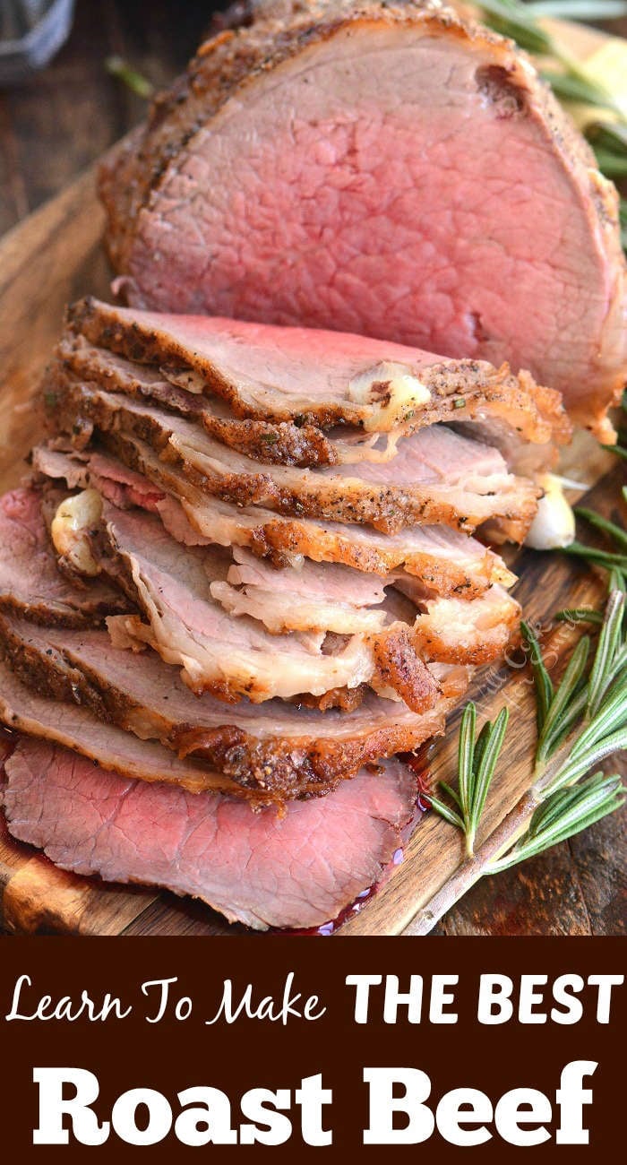 roast beef sliced on a wood cutting board with a sprig of rosemary 