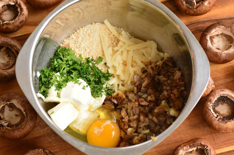 ingredients for the stuffing in a mixing bowl with mushroom caps around the bowl