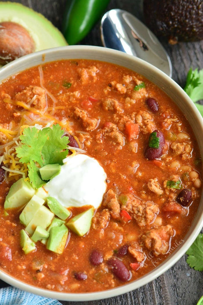 top view of turkey chili in a bowl with sour cream and avocado on top