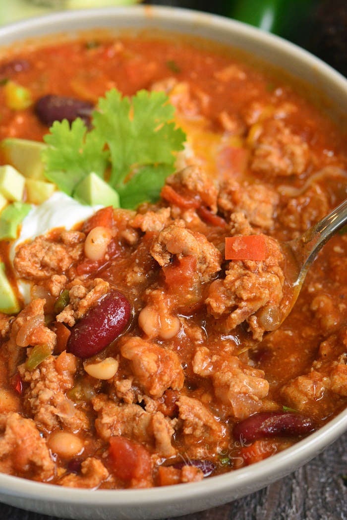 close up of spooning out turkey chili out of the bowl
