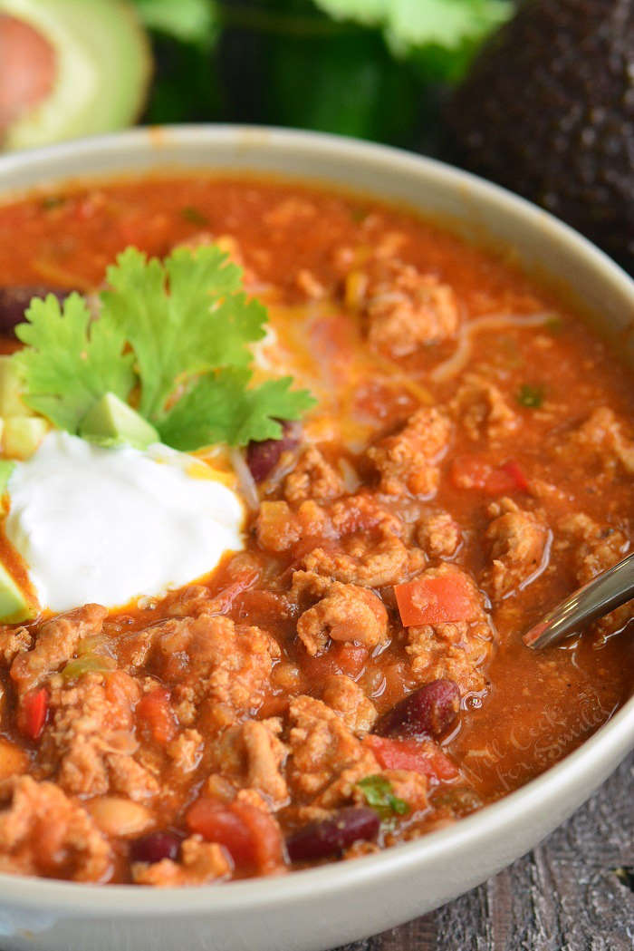 spooning turkey chili in a bowl 