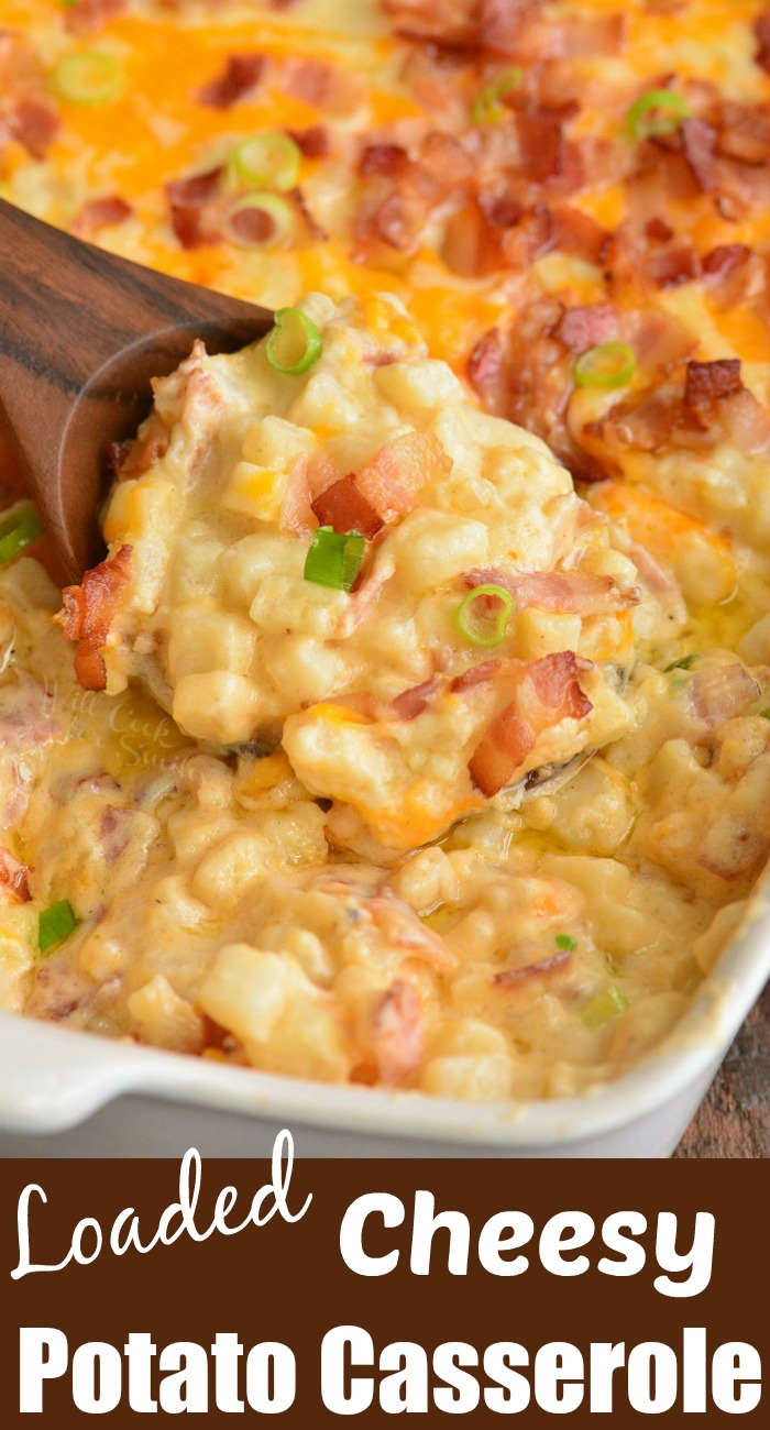 cheesy potato casserole with bacon and green onions in a casserole dish being scoped out with a wooden spoon 