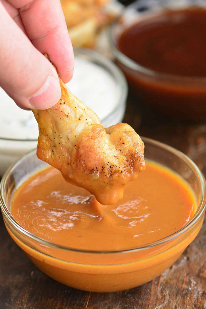 dipping chicken wing in sauce