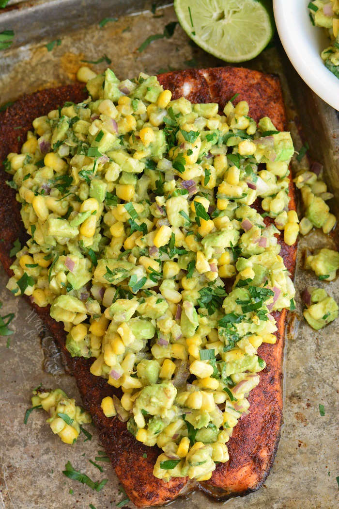 baked salmon with avocado salsa on top on a baking sheet 