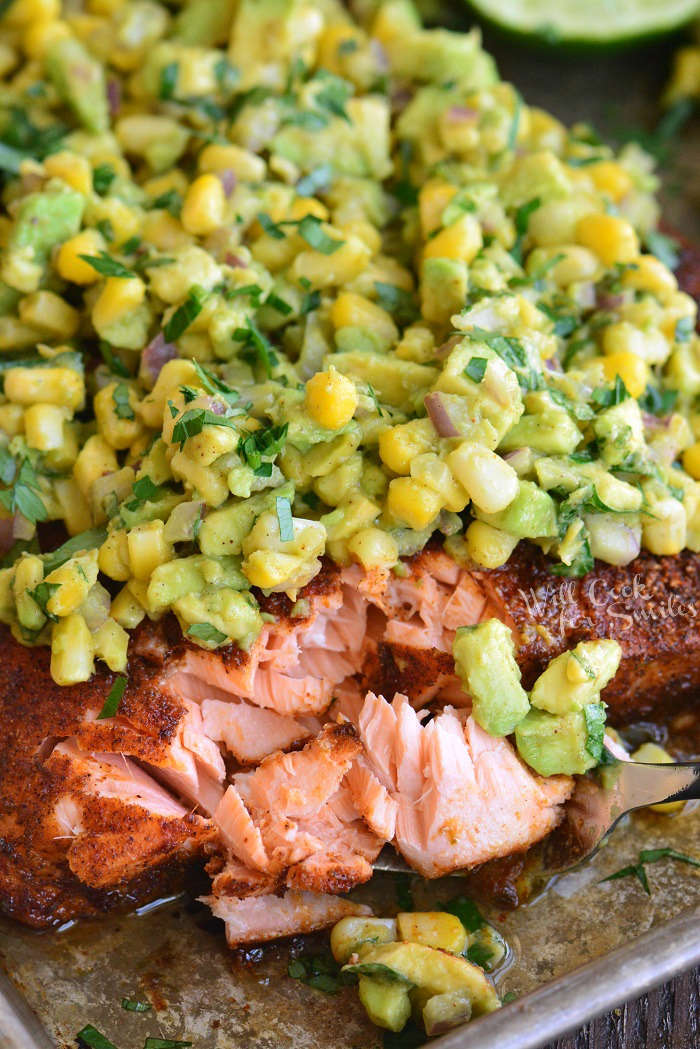 flaking off cooked salmon on a baking sheet 