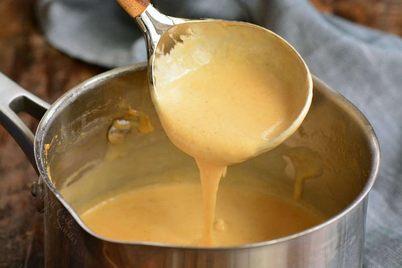 beer cheese in a pan being scooped out with a spoon 